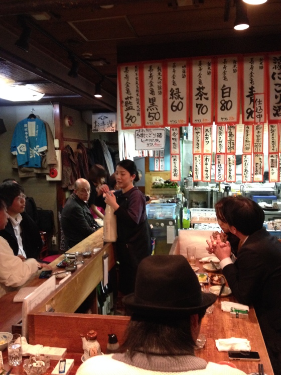 A Japanese lady served the sake from a large white bottle
